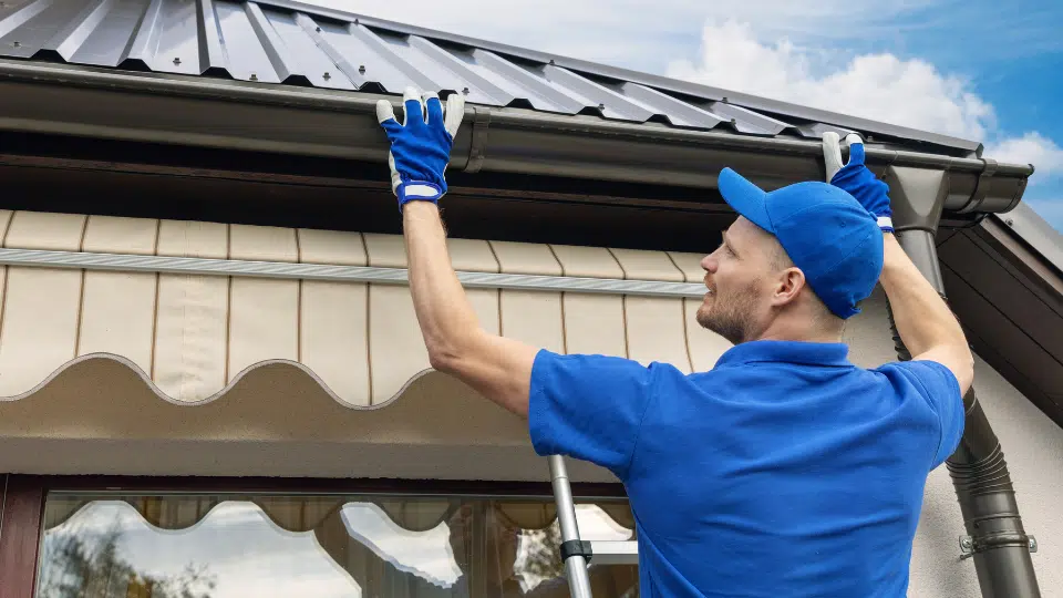man installing house roof rain gutter system