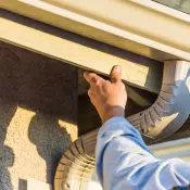 Worker Attaching Aluminum Rain Gutter and Down Spout to Fascia