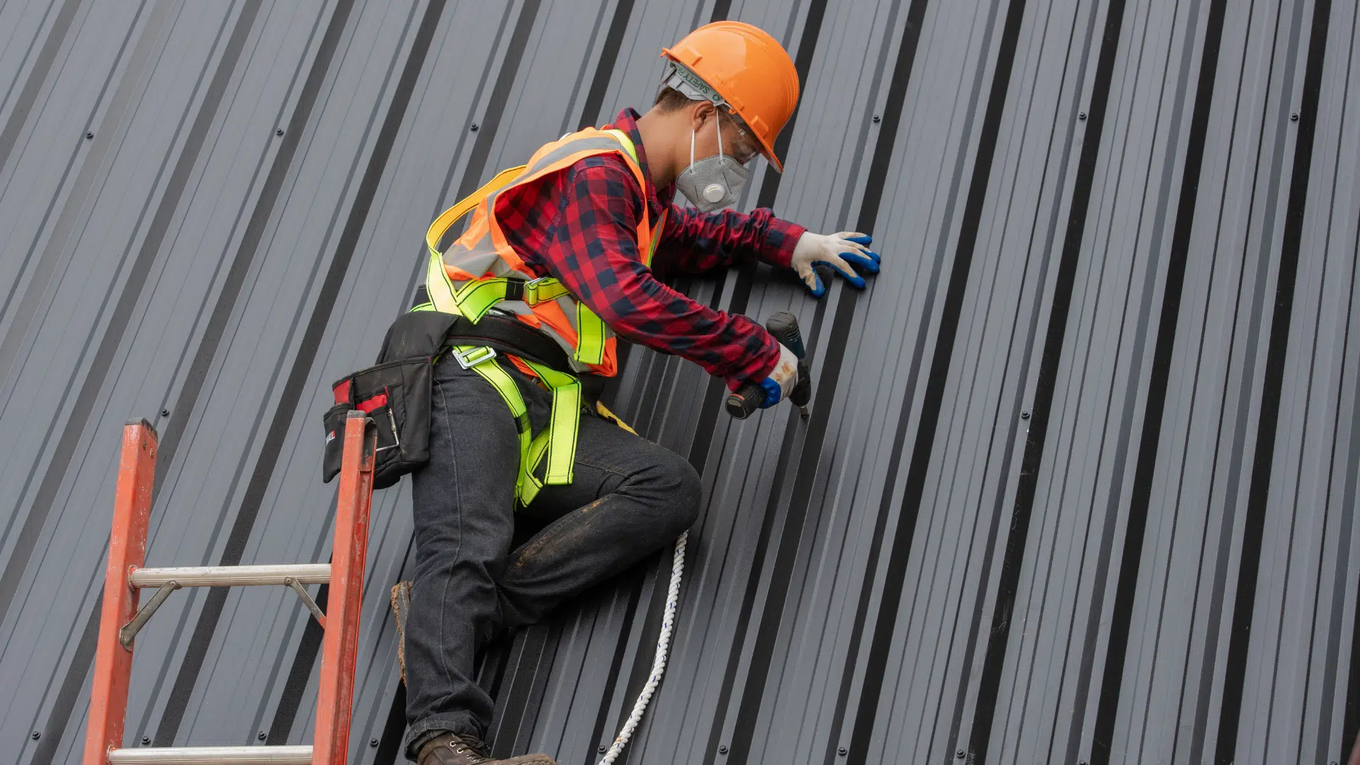 man drilling the grey roof