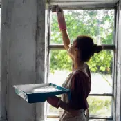 woman painting the wall near the window